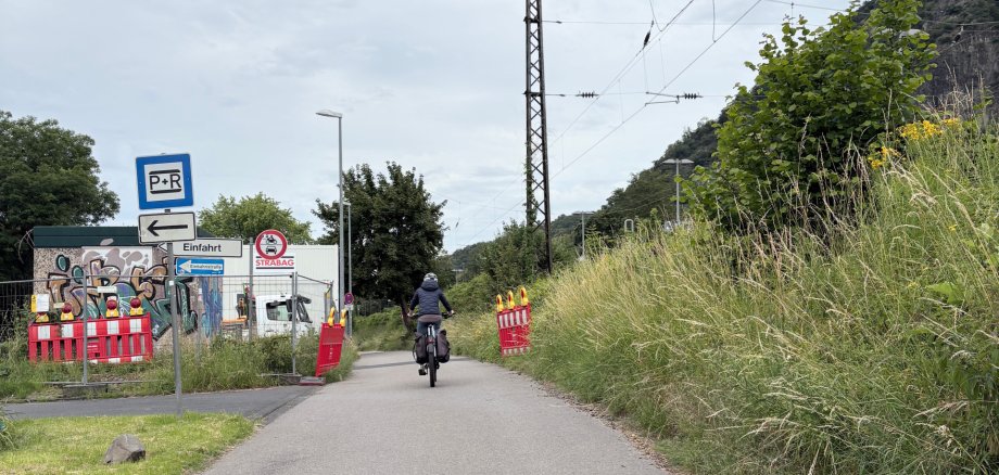 Radfahrerin auf dem Radweg am Bahnhof Rhöndorf neben der Bahnstrecke während der laufenden Modernisierungsarbeiten.