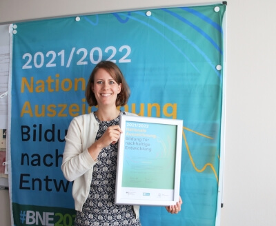Johanna Högner mit Urkunde vor einem Plakat der Bildung für nachhaltige Entwicklung