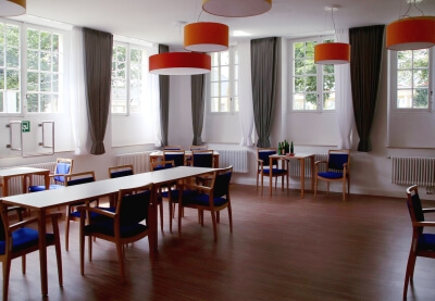 Raum mit Tischen und blauen Stühlen für den Seniorentreff