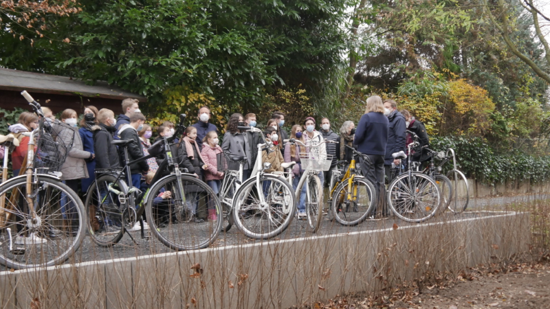 Gruppe mitKindern, Jugendlichen und Erwachsenen. Davor sind zahlreiche Fahrräder geparkt.