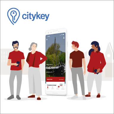 Das Bild zeigt das Logo der ity Key App und 4 Menschen neben einem übergroßen Smartphone