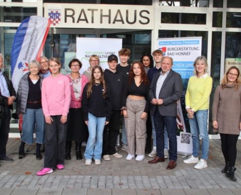 Eine Gruppe von Menschen unterschiedlichen Alters steht vor dem Rathaus Bad Honnef