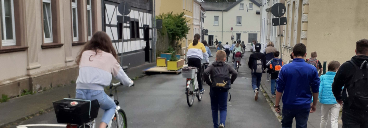 Fahrradfahrer und Fußgänger bewegen sich auf einer Straße in einer RIchutng