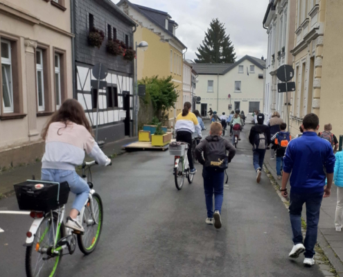 Fahrradfahrer und Fußgänger bewegen sich auf einer Straße in einer RIchutng